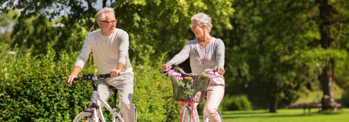 Man en een vrouw in hun pensioen blijven fit door te gaan fietsen in een park.