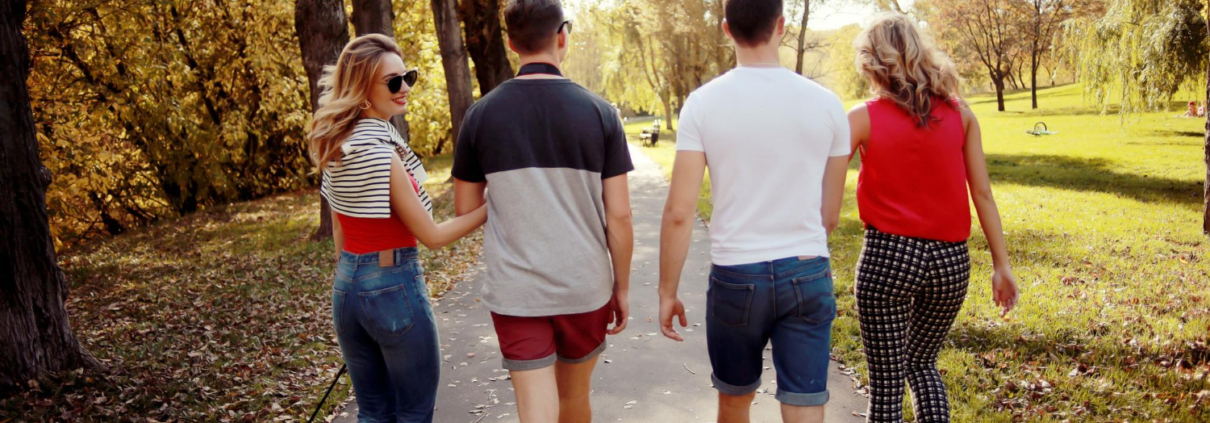 Groepje vrienden werken aan hun mentale gezondheid en gaan zonder jas een wandeling maken in het park terwijl de zon schijnt