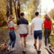 Groepje vrienden werken aan hun mentale gezondheid en gaan zonder jas een wandeling maken in het park terwijl de zon schijnt