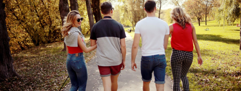 Groepje vrienden werken aan hun mentale gezondheid en gaan zonder jas een wandeling maken in het park terwijl de zon schijnt