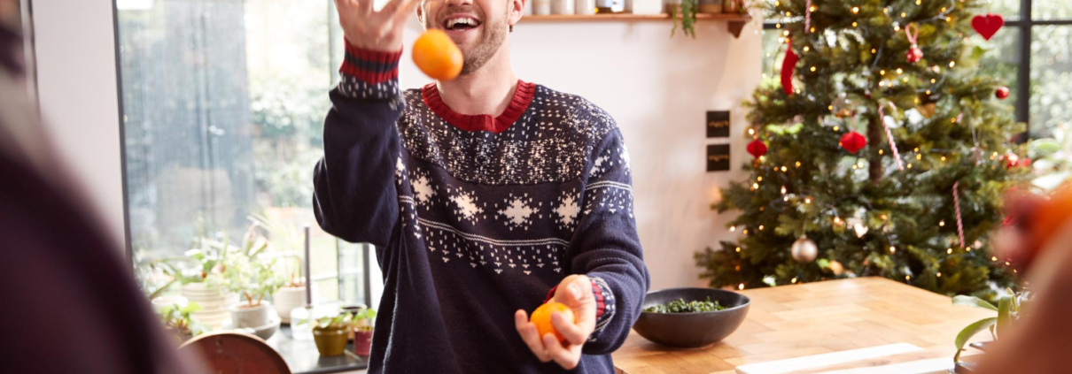 Man is aan het jongleren met fruit, één van zijn gezonde kerstcadeaus.
