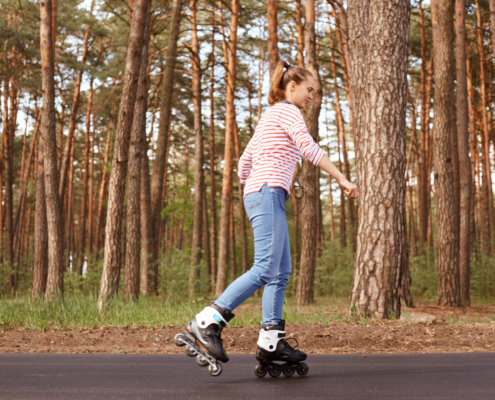 Een jonge dame doet aan de sport skeeleren op een weg in het bos.