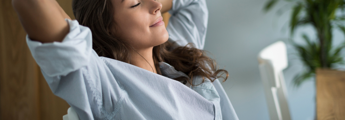 Een vrouw in een grijs shirt werkt aan haar ademhaling om weer tot rust te komen.