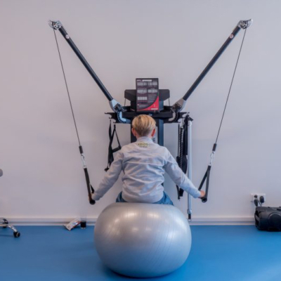 Een kind op een oefeningbal werkt aan kinderfysiotherapie en is bezig met een workout in de oefenzaal